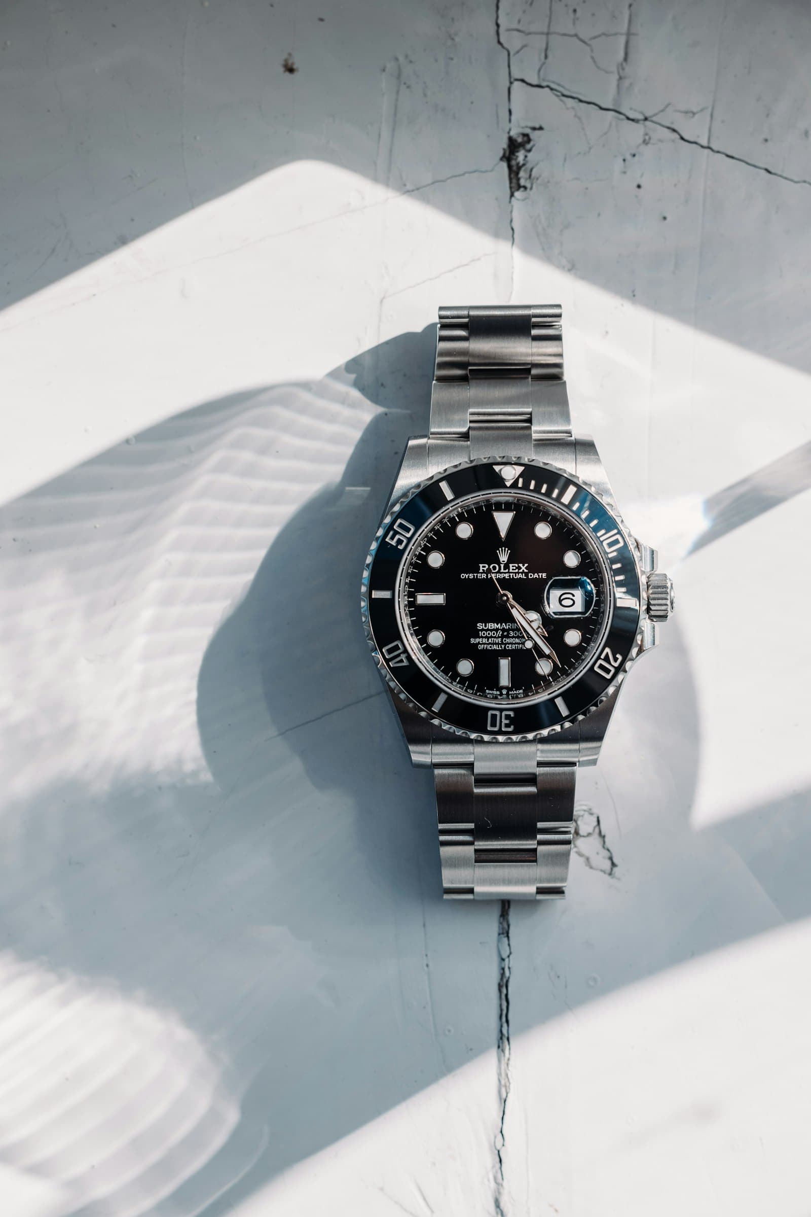 The Submariner laid flat on white cloth, black dial and black bezel, bracelet folded behind it